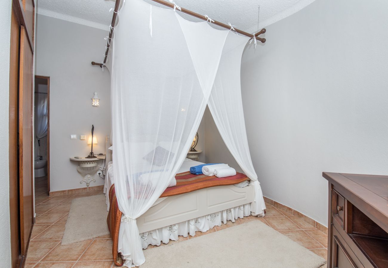double bedroom with bedside table, lamp, mosquito net above bed