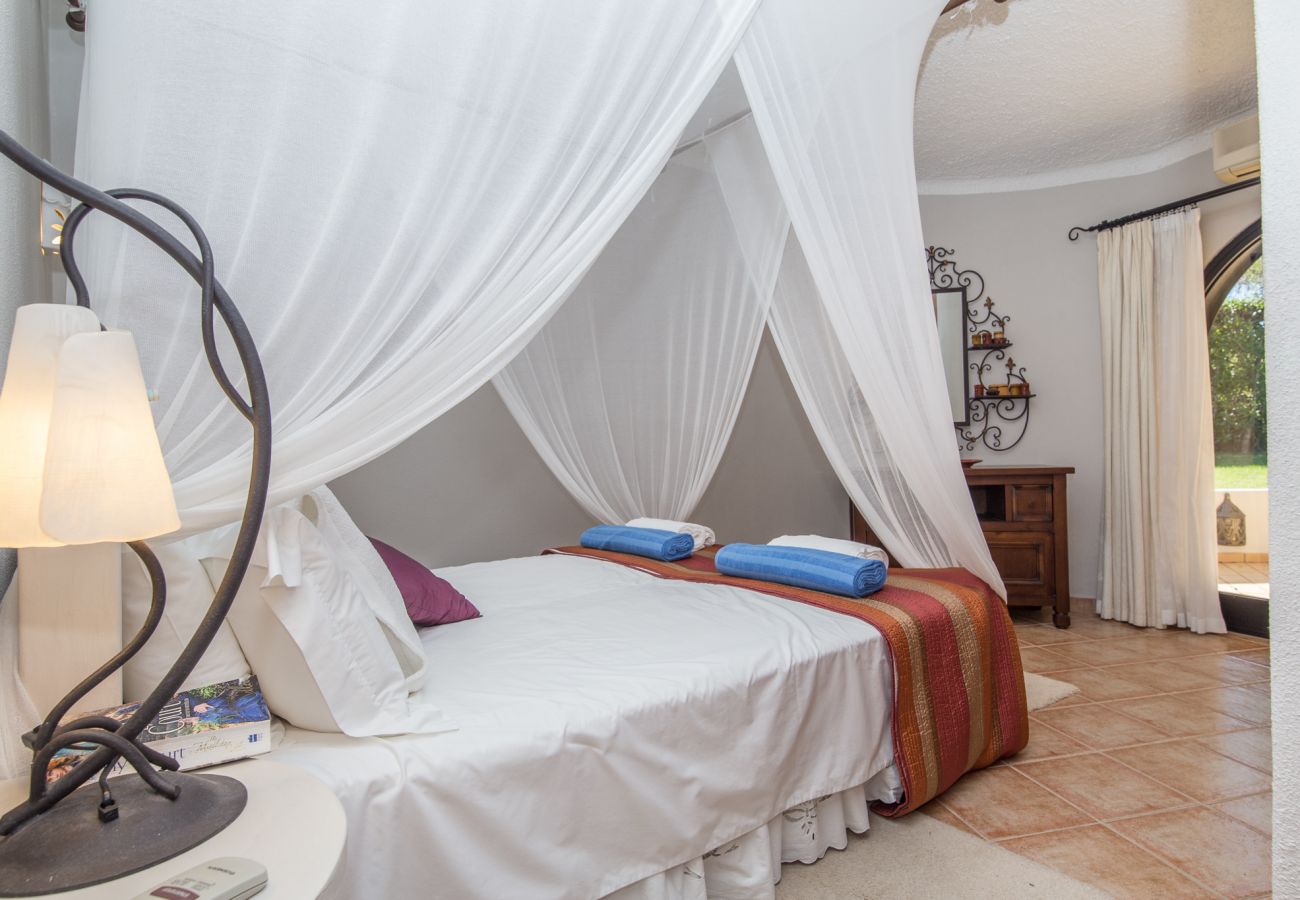 Double bedroom with French doors, integrated wardrobes and mosquito netting around bed