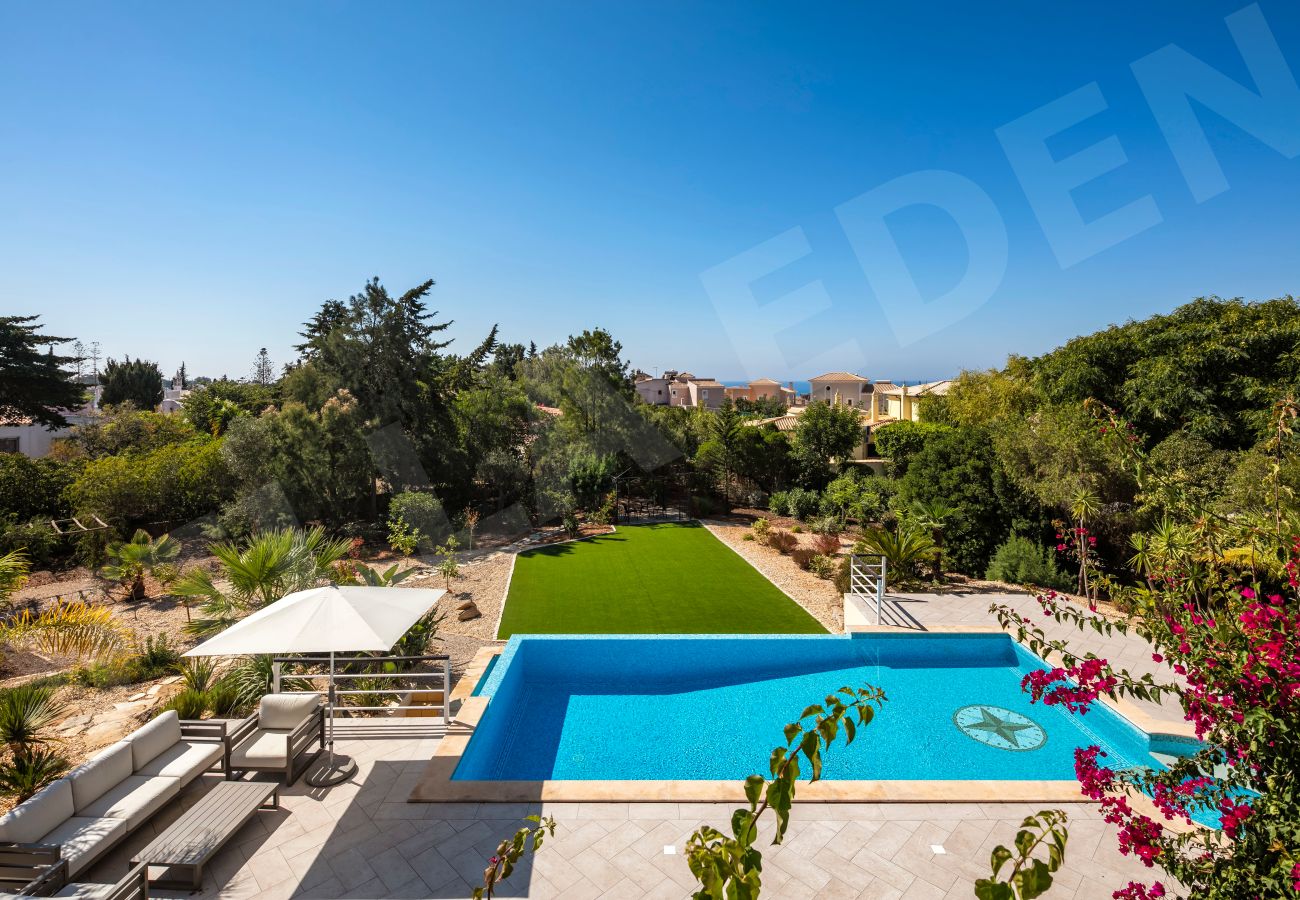 View of the pool, lawn, and distant sea from Villa Eden in Carvoeiro