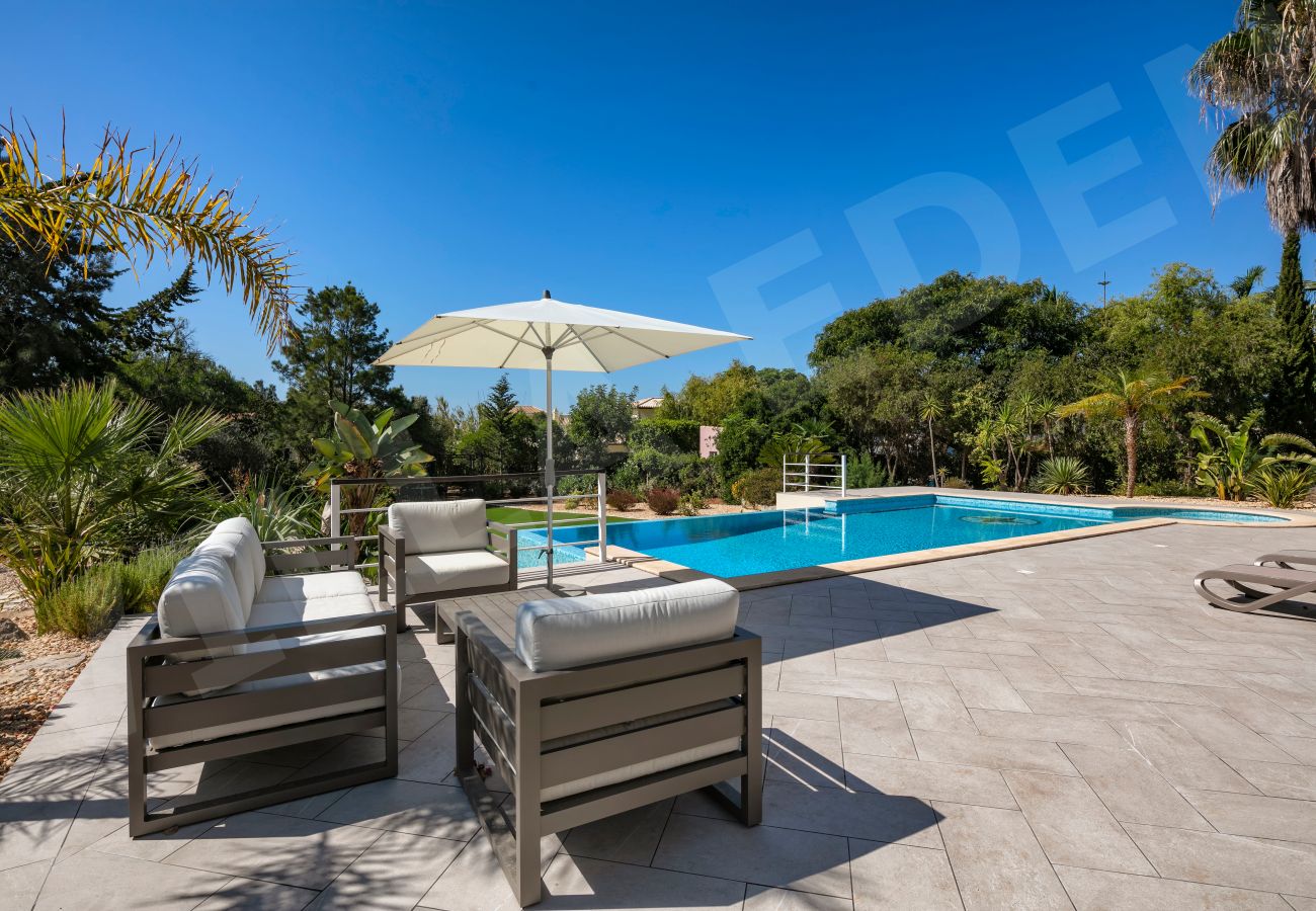 Cushioned poolside lounge area with umbrella at Villa Eden in Carvoeiro